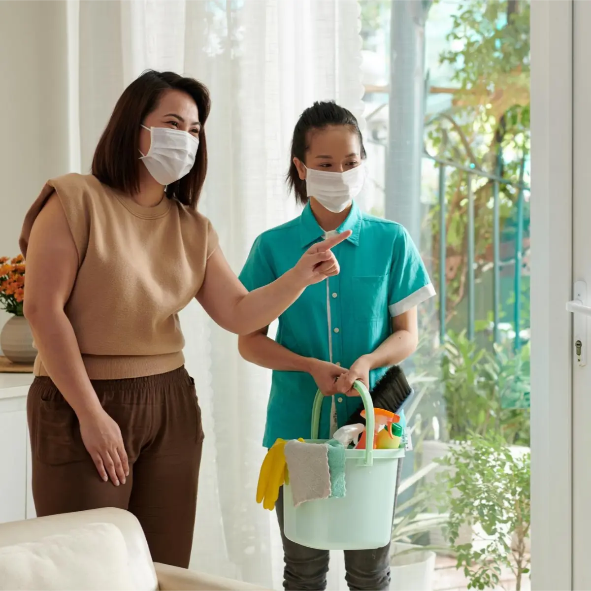 Homeowner and professional cleaner wearing masks and discussing tasks during cleaning services in Coquitlam