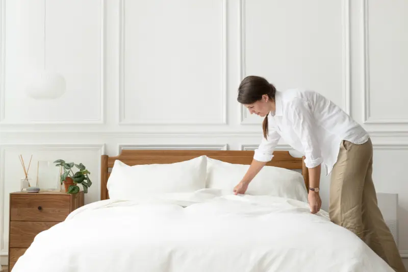 female cleaning professional making the bed of a bedroom during a thorough condo cleaning