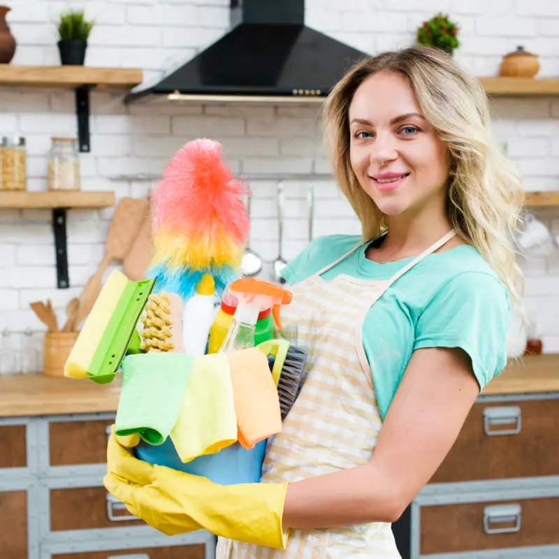 happy cleaning professional with the bucket of cleaning supplies in hand after home cleaning for seniors