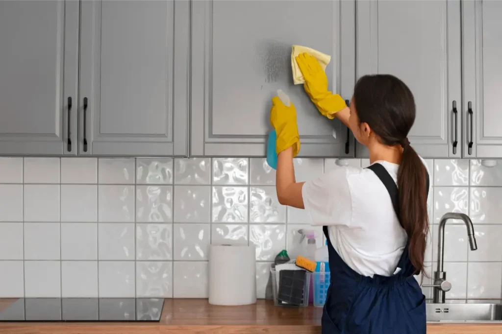 female cleaning professional sanitizing the cabinets of kitchen