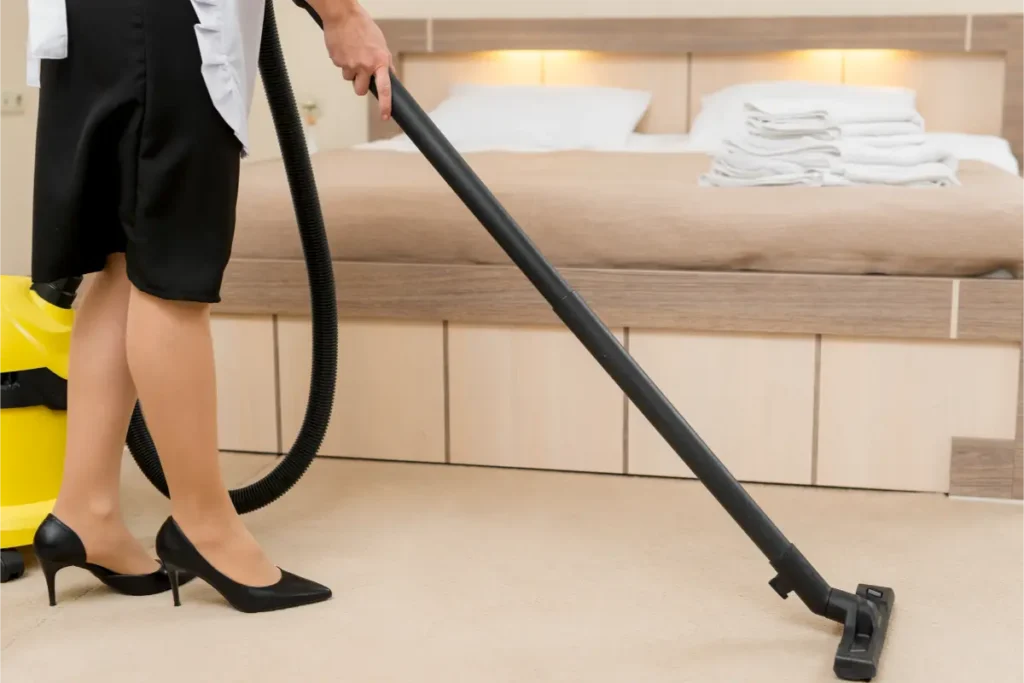 professional woman cleaner vacuuming the bedroom floor