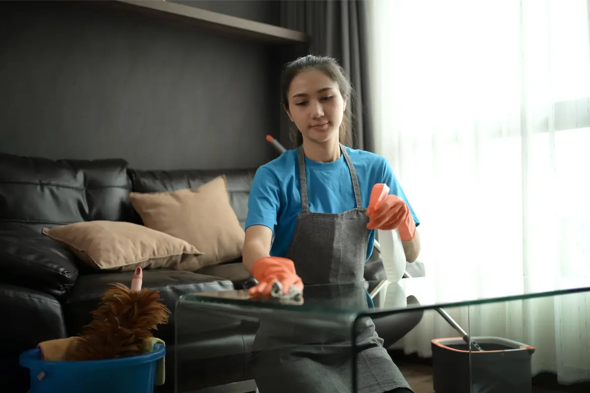 young professional cleaner wiping of the table during spring cleaning