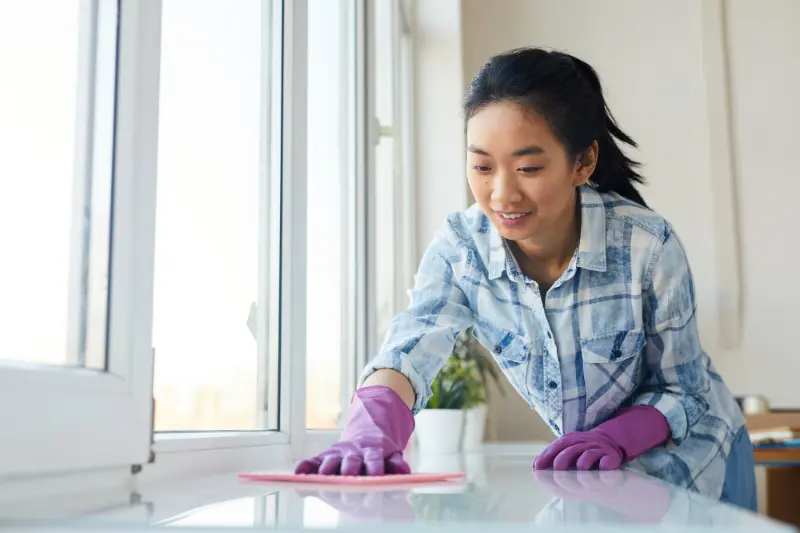 female professional cleaner scrubbing the table during weekly home cleaning