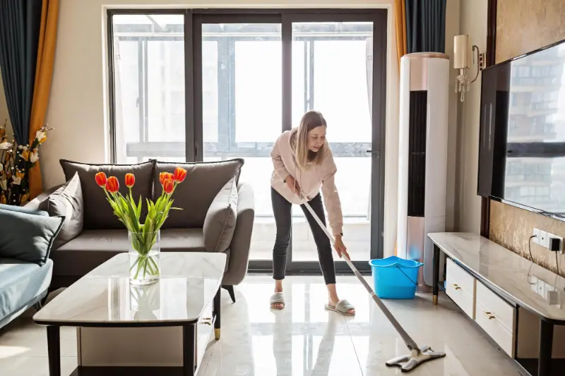 Woman mopping floor in bright living room during house cleaning