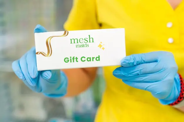 Female professional with gloves holding Mesh Maids gift card for cleaning services in Vancouver