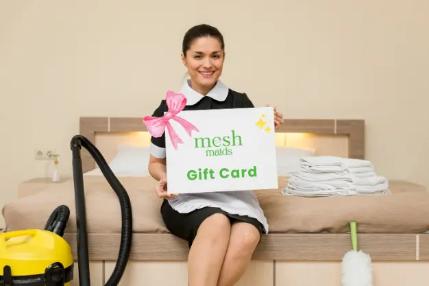 Happy young female professional holding Mesh Maids gift card for cleaning services in North Vancouver