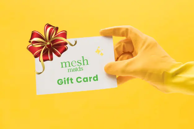Professional woman cleaner holding mesh Maids gift card for cleaning services in Coquitlam