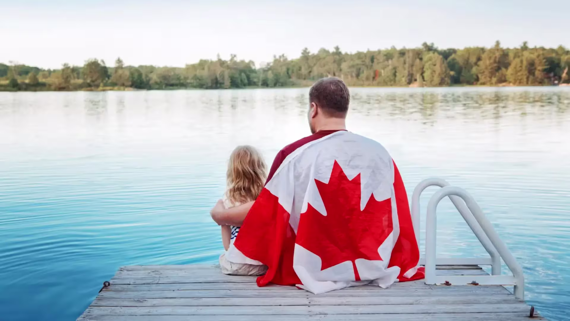 Father and daughter on a beach front with a Canadian flag