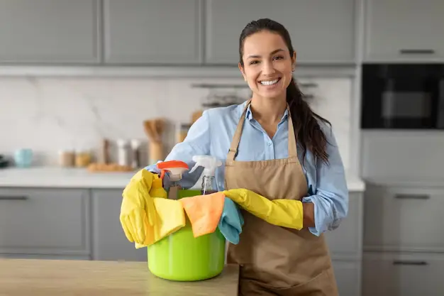 Young cheerful cleaning professional holding supplies during house cleaning services in North York