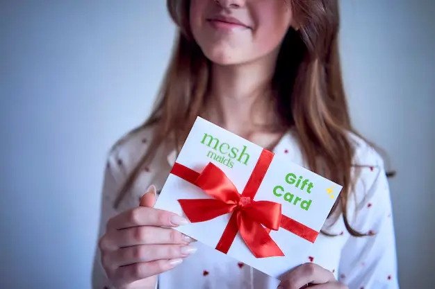 Young woman holding a Mesh Maids gift card for cleaning services in Etobicoke
