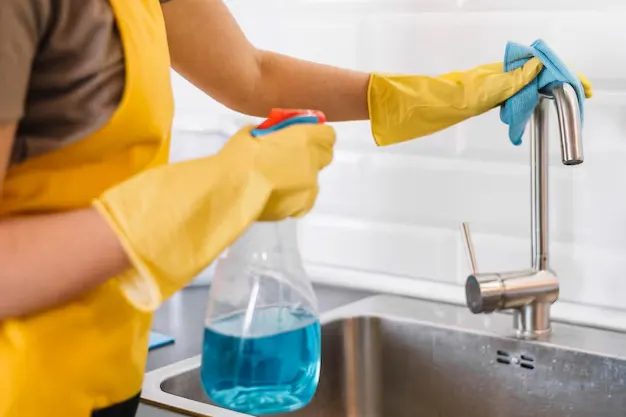 Young woman cleaning the tap in the kitchen during deep house cleaning services in Etobicoke