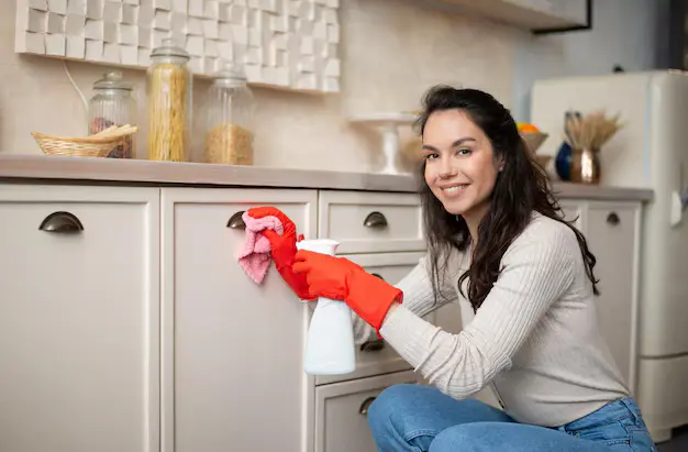 Cheerful Young lady cleaning kitchen during cleaning services in Vaughan