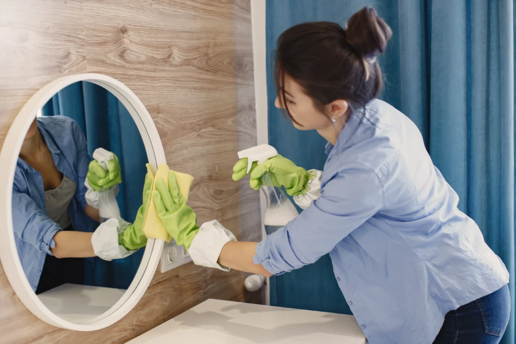 Woman professional cleaner cleaning mirror during cleaning services in Richmond Hill