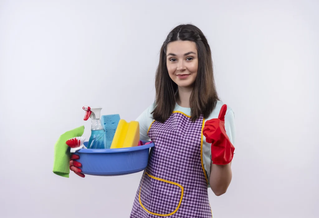 Young happy girl wearing apron with rubber gloves and cleaning supplies, showing thumbs up after house cleaning services in Richmond Hill