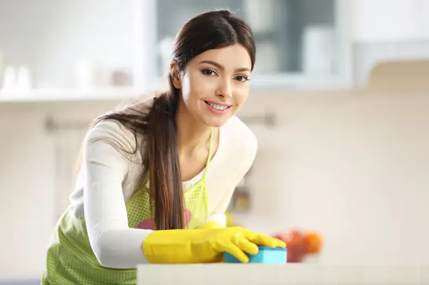 Young cheerful lady wiping off the table during professional house cleaning services in Calgary