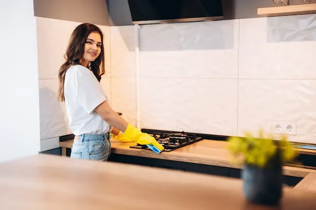 Young woman professional cleaner cleaning in kitchen during house cleaning services in Hamilton and Burlington