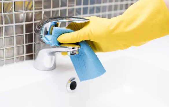 Female Mesh Maids cleaner cleaning bathroom faucet during house cleaning services in Kelowna, Lake Country & Vernon